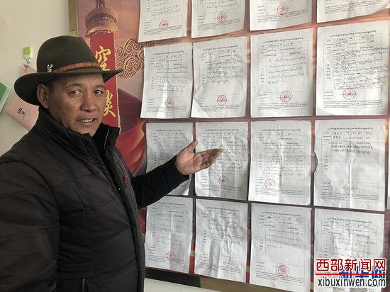 村委会书记次旺欧珠向记者介绍赤德村党支部党员公开承诺的任务。新华网 雪珍摄